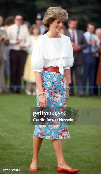 Diana, Princess of Wales, wearing a blue floral patterned pencil skirt with a red belt and white blouse, attends a polo match at Cirencester Park...