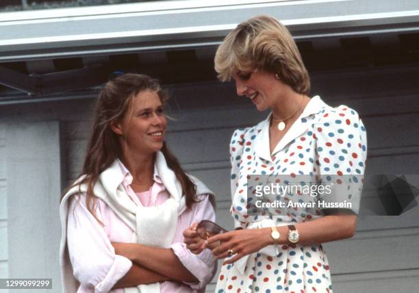 Diana Princess of Wales, wearing a white dress with red and blue polkadots, talks to Lady Sarah Armstrong-Jones, as they attend a polo match at...