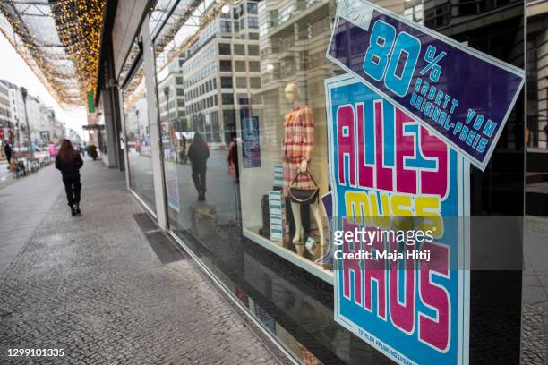 Woman walks past a closed shop offering discount due closing during the second wave of the coronavirus pandemic on January 28, 2021 in Berlin,...