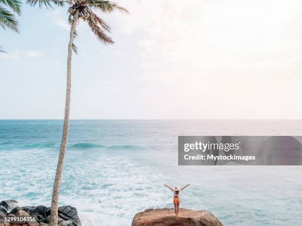 mujer en roca sobre el mar se levanta los brazos de ancho - aura fotografías e imágenes de stock