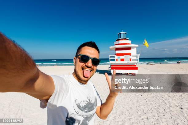 young man in sunglasses taking a selfie at south beach, miami, usa - protruding ストックフォトと画像