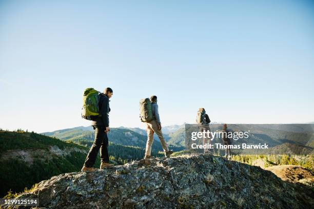 father and daughters hiking along rocky ridgeline during backpacking trip - wandelen stockfoto's en -beelden