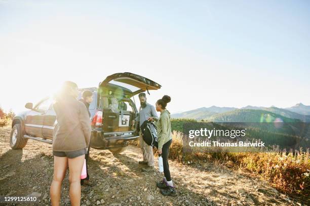 father and daughters preparing to begin backpacking trip at back of car - back of car stock-fotos und bilder