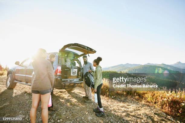 father and daughters preparing to begin backpacking trip at back of car - open roads world premiere of mothers day arrivals stockfoto's en -beelden