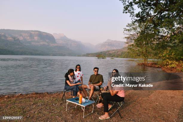 family sitting on chairs and having fun together by the beautiful lake - lakeshore stock pictures, royalty-free photos & images