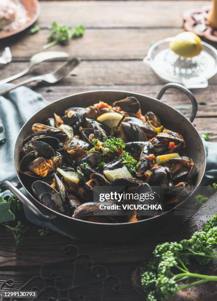 close up of mussels in cooking dish lemon slices and tasty sauce on rustic kitchen table - clams 個照片及圖片檔