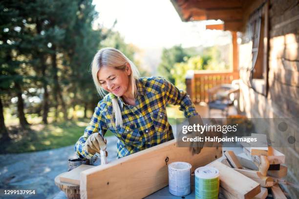 senior woman painting wood outdoors, art and craft diy project. - timber yard stock pictures, royalty-free photos & images