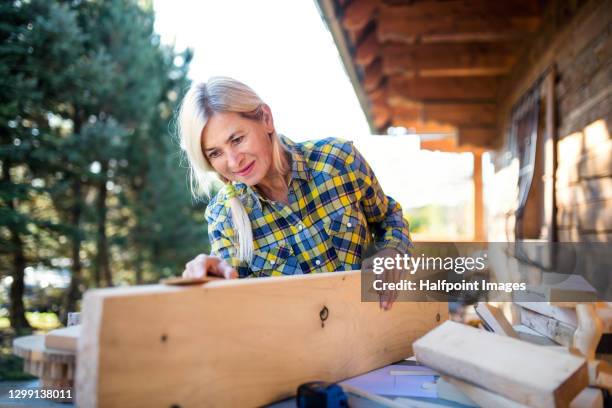 senior woman sanding wood outdoors, art and craft diy project. - timber yard stock pictures, royalty-free photos & images