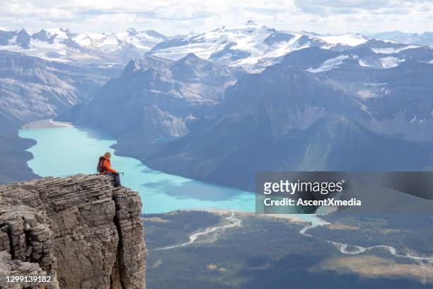 female mountaineer relaxes on mountain ridge in the morning - distant stock pictures, royalty-free photos & images