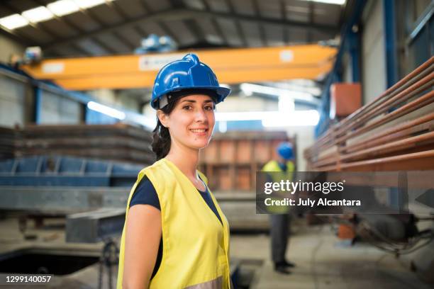 hübsche bauarbeiterin frau in der fabrik lächelnd in die kamera schauen - hispanic construction worker stock-fotos und bilder