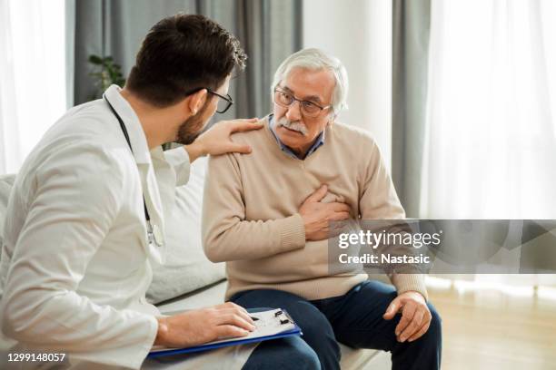 young doctor and senior man having a conversation about heart condition - heart attack stock pictures, royalty-free photos & images