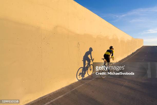 junger wettbewerbsfähiger straßenradfahrer - blurred running sunset stock-fotos und bilder