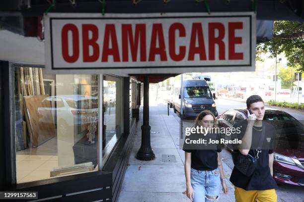 Pedestrians walk past the Leading Insurance Agency, which offers plans under the Affordable Care Act on January 28, 2021 in Miami, Florida. President...