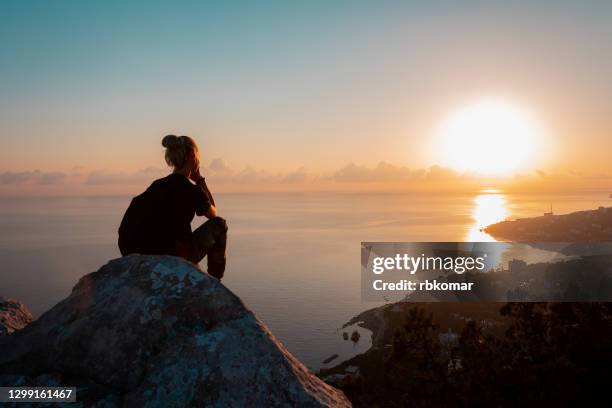 hiker rest on the edge of a high cliff with sunset views of the city and the sea - oportunidad fotografías e imágenes de stock