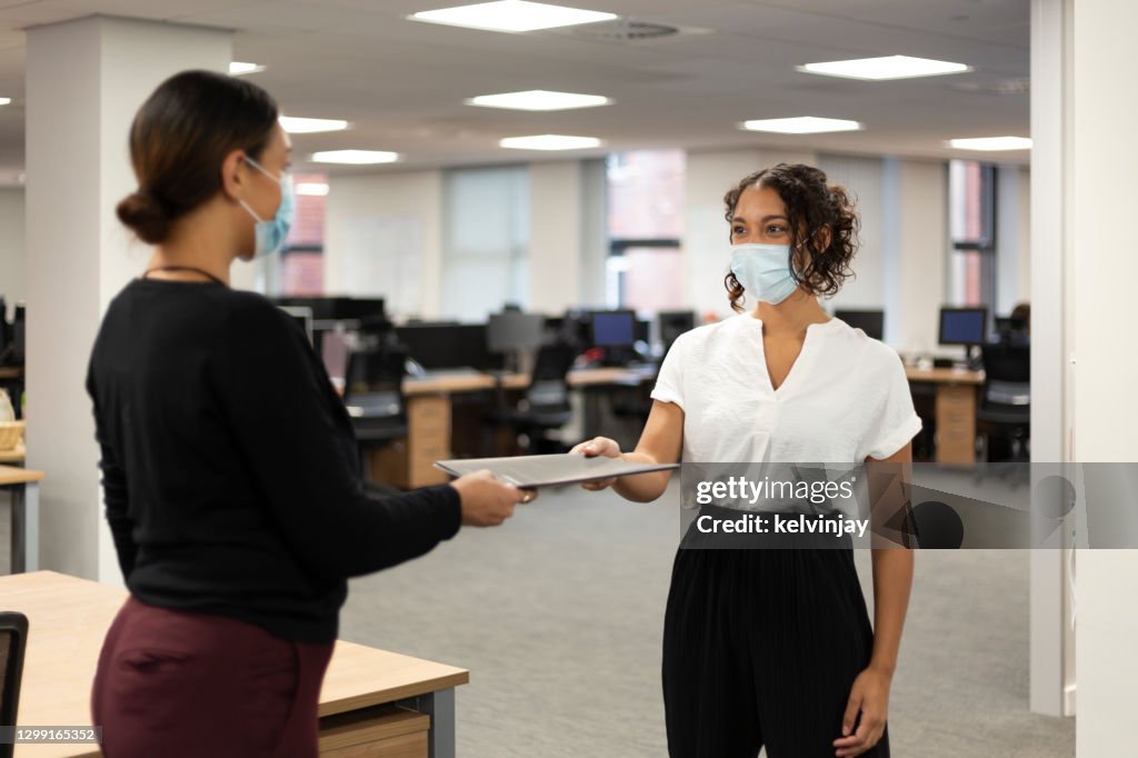 Young women working in an office wearing facemasks