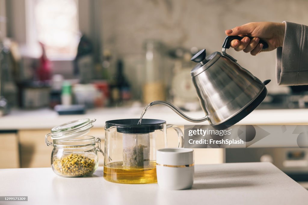 Mano di una donna che prepara il tè alla camomilla