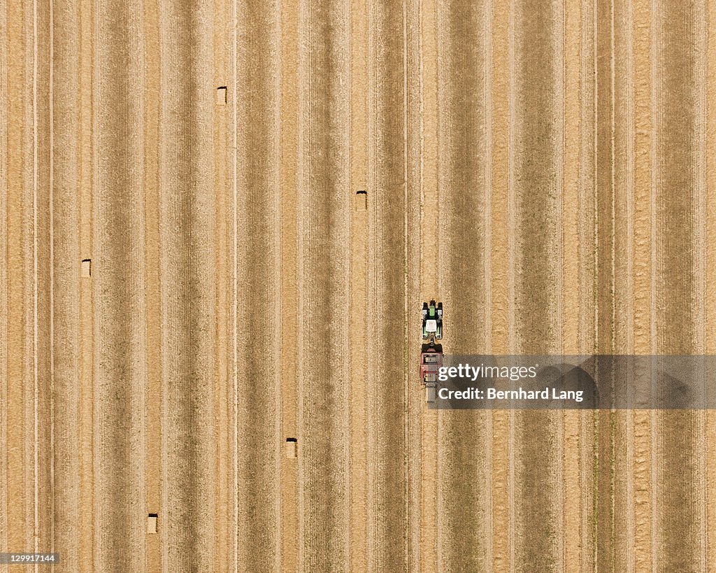 Tractor with bales of hay in field, aerial view