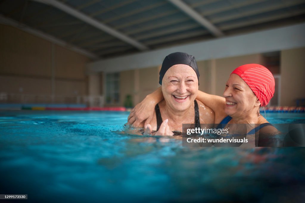 Zwei Seniorinnen umarmen sich im Hallenbad