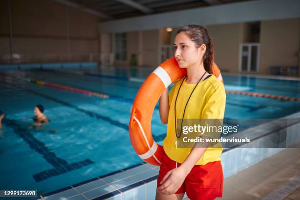 lifeguard walking with lifebuoy in indoor pool - life guard stock pictures, royalty-free photos & images