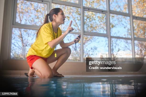 salvavidas con temporizador que da instrucciones a los nadadores en la piscina cubierta - lifeguard fotografías e imágenes de stock