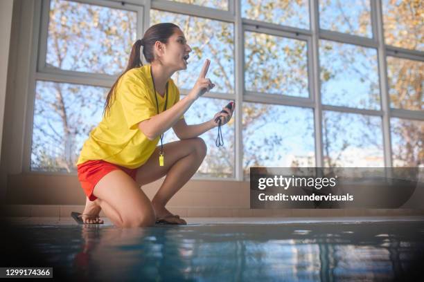 lifeguard holding timer giving instructions to swimmers in indoor pool - swimming coach stock pictures, royalty-free photos & images