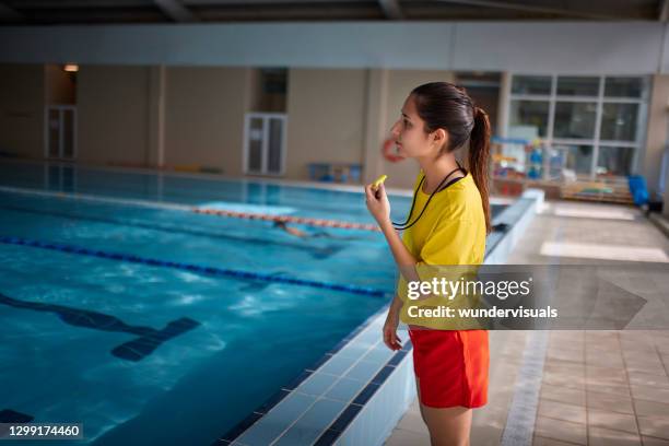 rettungsschwimmer bläst pfeife im hallenbad - bademeister stock-fotos und bilder