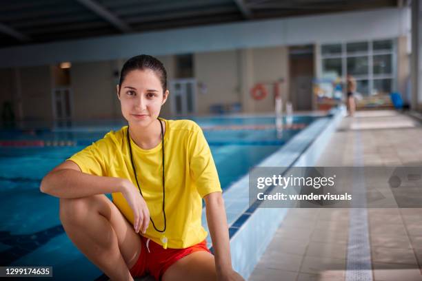 primer plano de socorrista sonriendo mirando sentado en el lado de la piscina cubierta - lifeguard fotografías e imágenes de stock