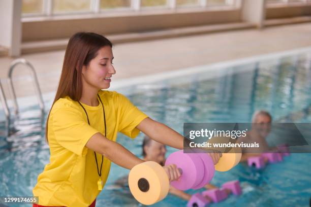 coach instructing water aerobics class for group of seniors - swimming coach stock pictures, royalty-free photos & images