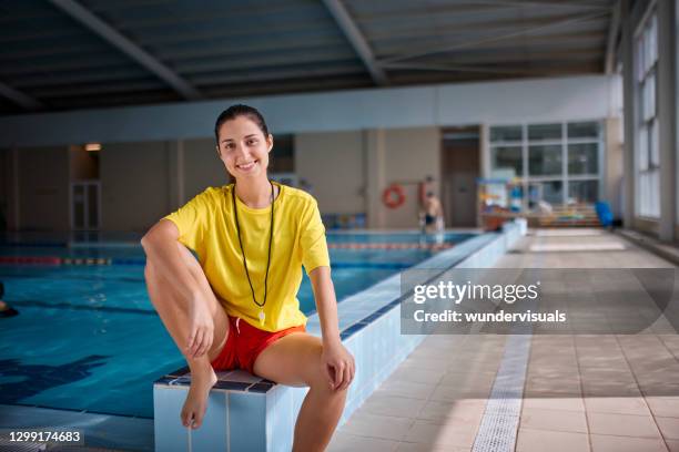 retrato de socorrista femenina sentada en el lado de la piscina cubierta - lifeguard fotografías e imágenes de stock