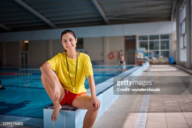 portrait of female lifeguard sitting on indoor pool side - teacher portrait stock pictures, royalty-free photos & images