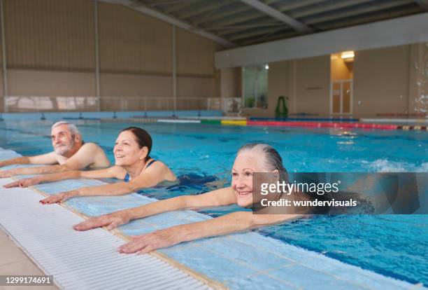 gruppe von senioren, die am pool planschfüße beim training im pool halten - adult gymnast feet stock-fotos und bilder