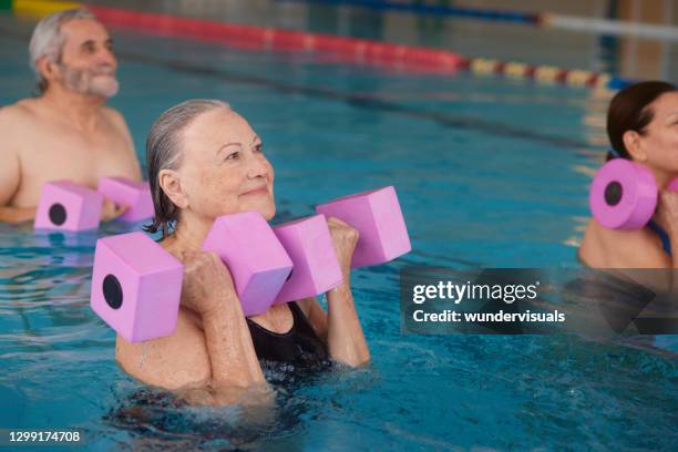 hogere vrouw die wapens met halters in aerobicsklasse uitoefent - aqua aerobics stockfoto's en -beelden