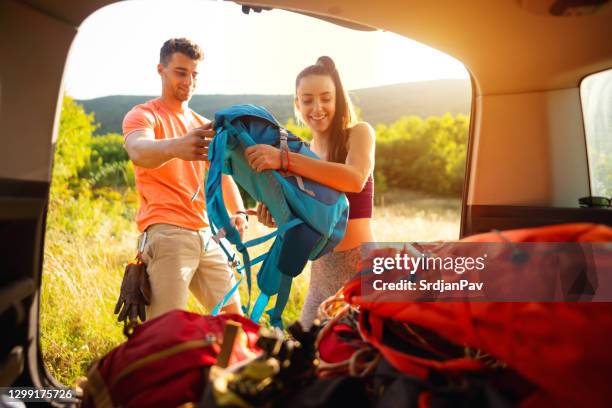 young couple  unloading the car trunk and getting ready for adventure - car camping luggage imagens e fotografias de stock
