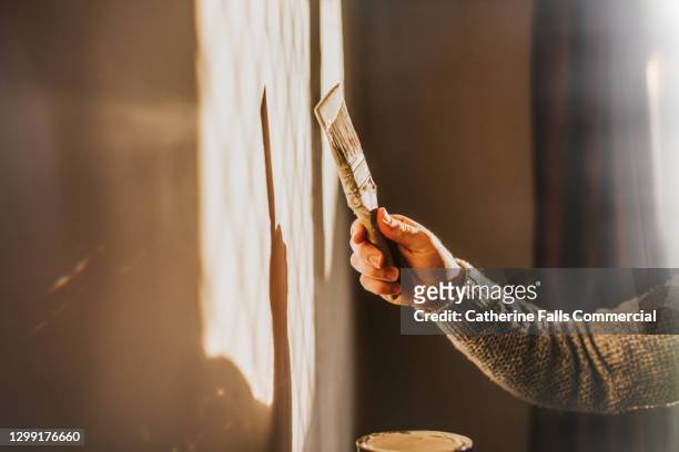 decorating - painting a wall with a paintbrush - effort stock pictures, royalty-free photos & images