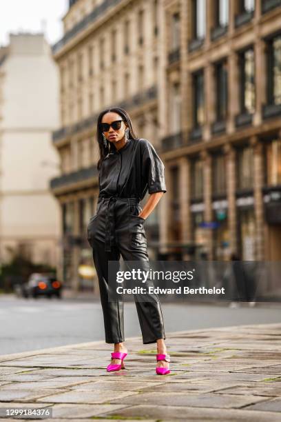 Emilie Joseph wears sunglasses from Gentle Monster, bejeweled earrings from Isabel Marant, a black leather jumpsuit from Mango, pink bejeweled heels...