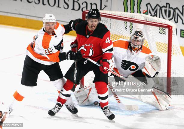 Nate Prosser and Carter Hart of the Philadelphia Flyers defend the net against Miles Wood of the New Jersey Devils during the second period at the...