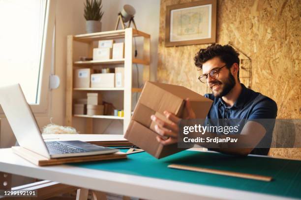 small online business owner preparing deliveries in the office and smiling - parcel laptop stock pictures, royalty-free photos & images