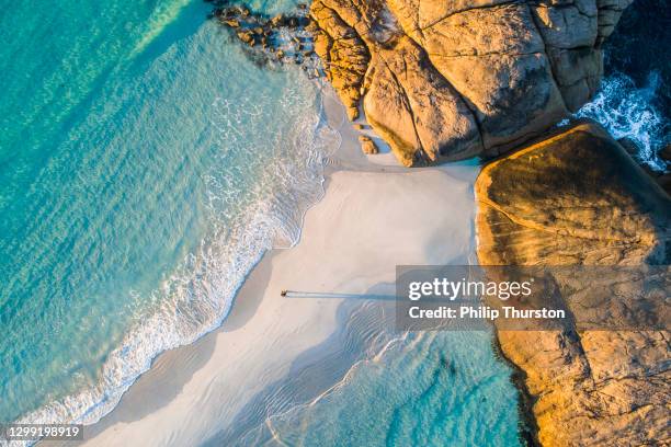 de luchtfoto van de kustlijn van aquamarine oceaan en mens die langs wit zandbankstrand loopt - beaches stockfoto's en -beelden