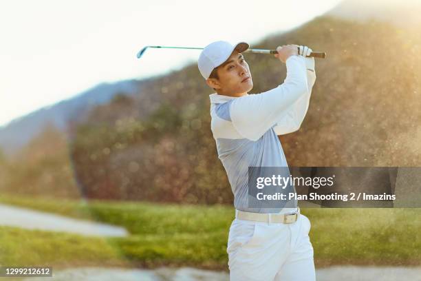 a man swinging a golf club - swinging golf club stock pictures, royalty-free photos & images