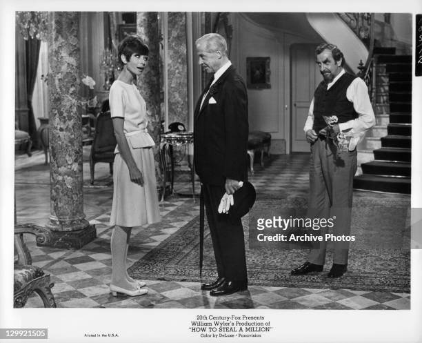 Audrey Hepburn talking to unidentified man as Hugh Griffith watches in a scene from the film 'How To Steal A Million', 1966.