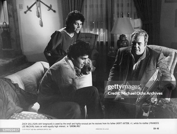 Zach Galligan, Frances Lee McCain and Hoyt Axton looking into a box in a scene from the film 'Gremlins', 1984.