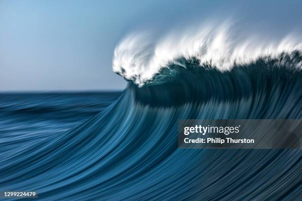 large blue cresting wave breaking in the open ocean on a sunny day - big wave stock pictures, royalty-free photos & images