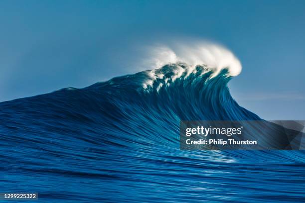 large blue cresting wave breaking in the open ocean on a sunny day - big wave stock pictures, royalty-free photos & images