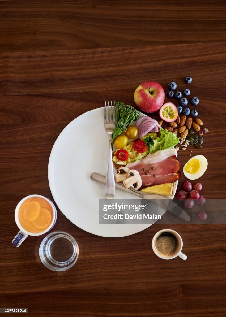 A table setting (on a wooden table) arranged to illustrate the concept of intermittent fasting.