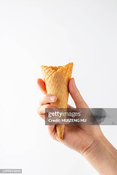 hand holding ice cream cone on white background - freezing hands stock-fotos und bilder