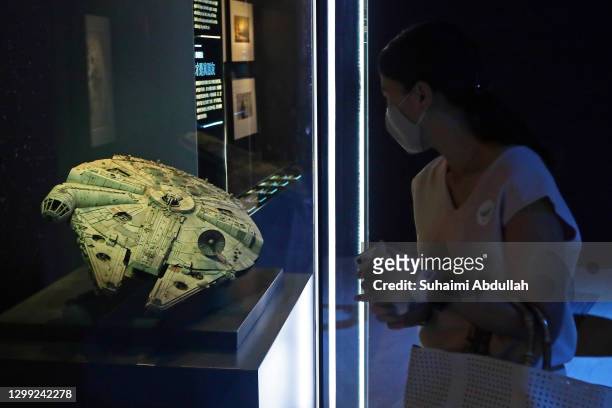 Lady wearing protective mask looks at a Millenium Falcon starship at The Star Wars Identities exhibition during a media preview at The ArtScience...