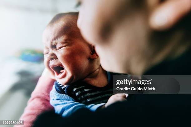 baby girl holding by mother crying out loud. - daughter crying stock pictures, royalty-free photos & images