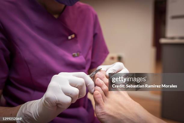 a chiropodist taking care of foot - removing hard skin with special tool. - pedicure foto e immagini stock