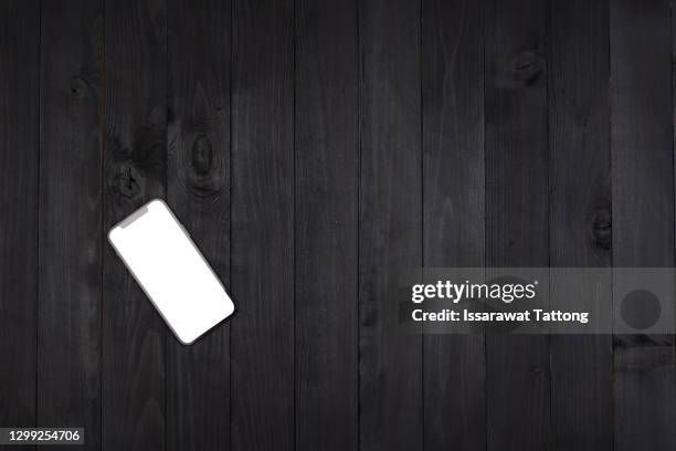 mobile phone with empty screen on black wooden desktop. top view - notepad table stockfoto's en -beelden