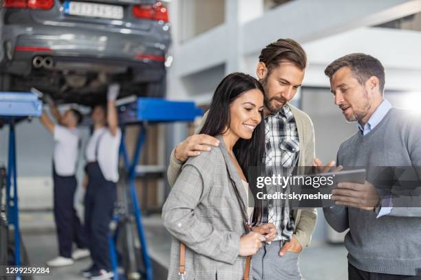 manager adulto medio e giovane coppia che utilizza il touchpad nell'officina di riparazione automatica. - carrozzeria foto e immagini stock